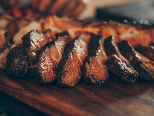 Slices of perfectly seared steak arranged on a wooden cutting board, juicy and caramelized, ready to be served and enjoyed.